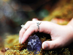 A woman's hand holding an amethyst crystal in the forest