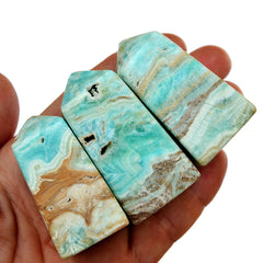 Three small blue aragonite obelisks on hand with white background
