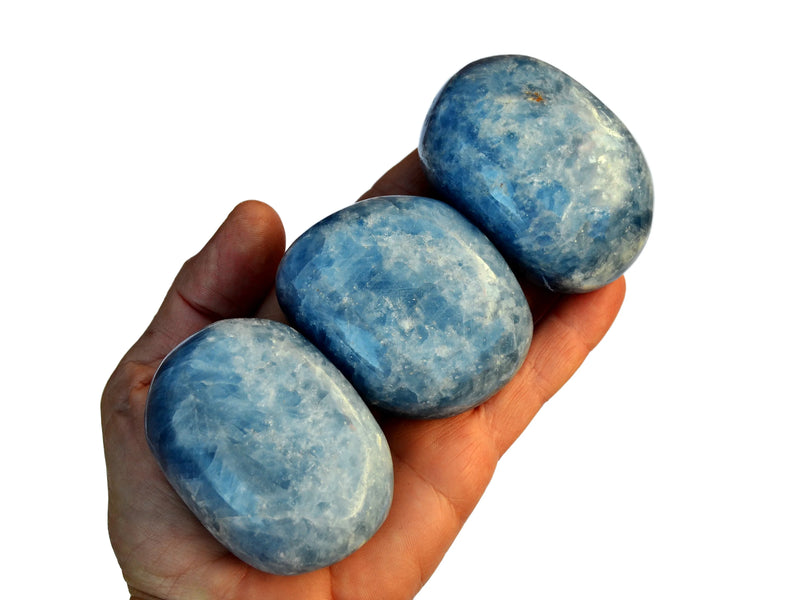 Three blue calcite palm stones on hand with white background
