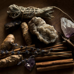 White sage, cinnamon, lavender, quartz crystal and amethyst crystal on a wood table