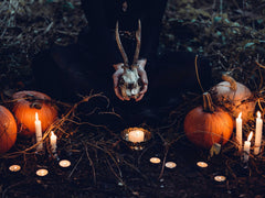 Ram's head, candles, and pumpkins on a Samhain night in the woods