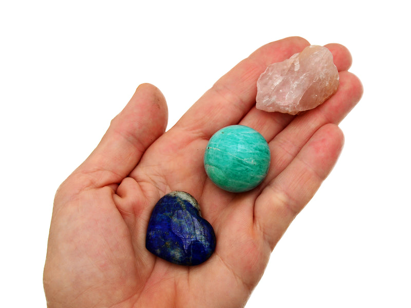 Raw pink quartz, amazonite sphere and lapis lazuli heart 30mm on hand with white background