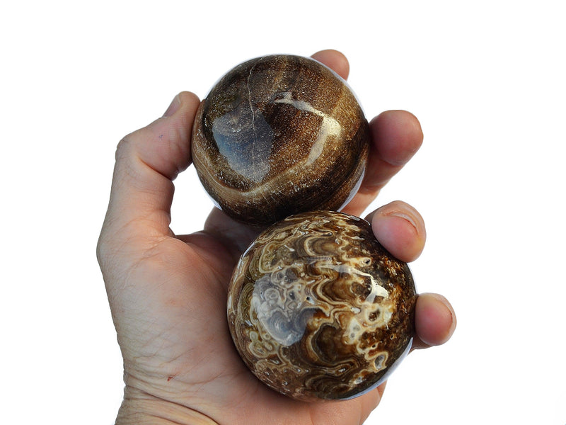 Three chocolate calcite sphere stones 50mm-60mm on hand with white background