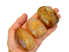 Three small yellow hematoid quartz free forms on hand with white background