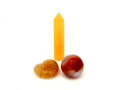 Small orange calcite point, golden healer quartz heart and carnelian sphere on white background