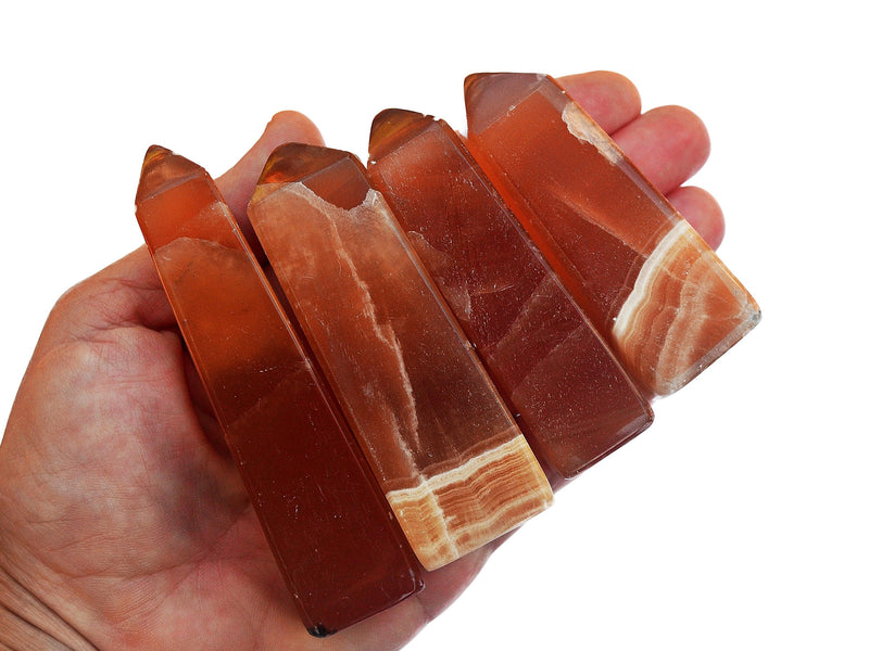 Four honey calcite crystal towers 75mm-90mm on hand with white background