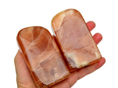 Two large honey calcite free forms 90mm on hand with white background