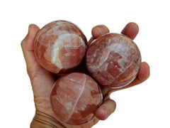 Three rose calcite sphere 55mm-60mm on hand with white background