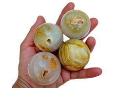 Four pink banded onyx sphere stones 50mm on hand with white background