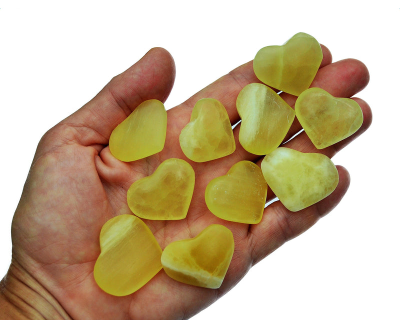 Ten lemon calcite crystal hearts 25mm-30mm on hand with white background