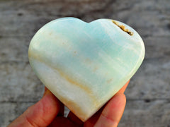 One large blue caribbeancalcite heart crystal 95mm on hand with wood background 