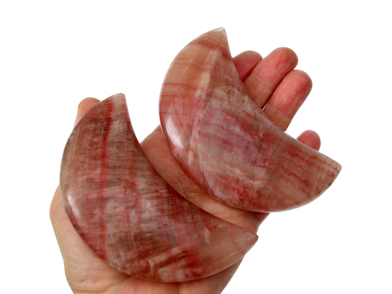 Two large rose calcite moons on white background