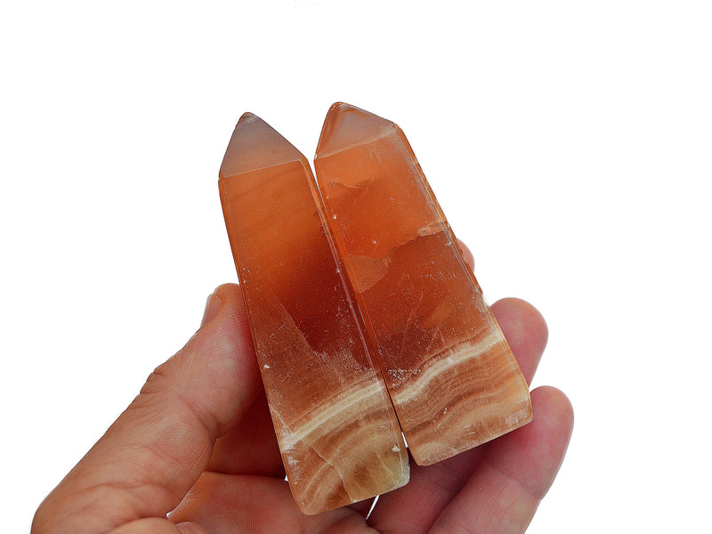 Two honey calcite crystal obelisks 60mm on hand with white background