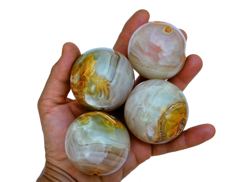 Four pink banded onyx sphere stones 55mm on hand with white background