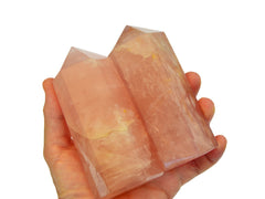 Two large pink quartz towers on hand with white background