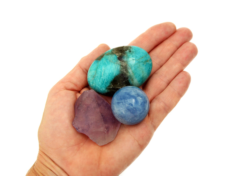 Small raw amethyst, blue calcite sphere and amazonite palm stone on hand with white background