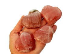 Four rose calcite heart crystals 50mm-60mm on hand with white background