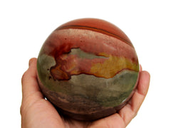 Large polychrome jasper crystal sphere 90mm on hand with white background