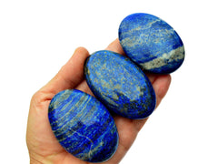 Three lapis lazuli palm stones 60mm on hand with white background