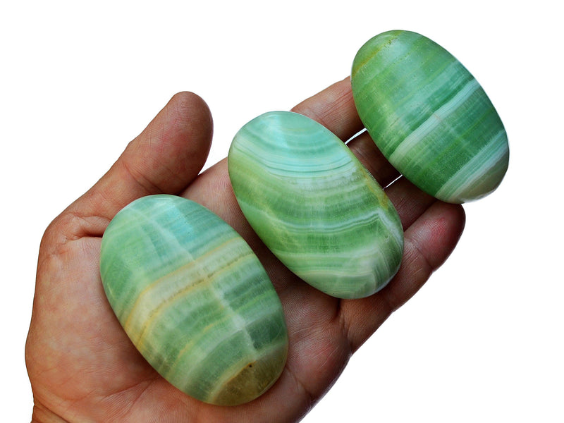 Three pistachio calcite palm stones 65mm-70mm on hand with white background