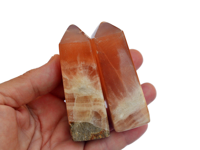 Two honey calcite crystal towers 60mm on hand with white background