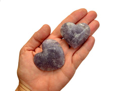 Two purple lepidolite hearts 45mm-50mm on hand with white background