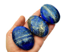 Three lapis lazuli palm stones 50mm on hand with white background