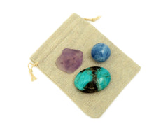 Raw amethyst, blue calcite sphere and amazonite palm stone on small jute bag
