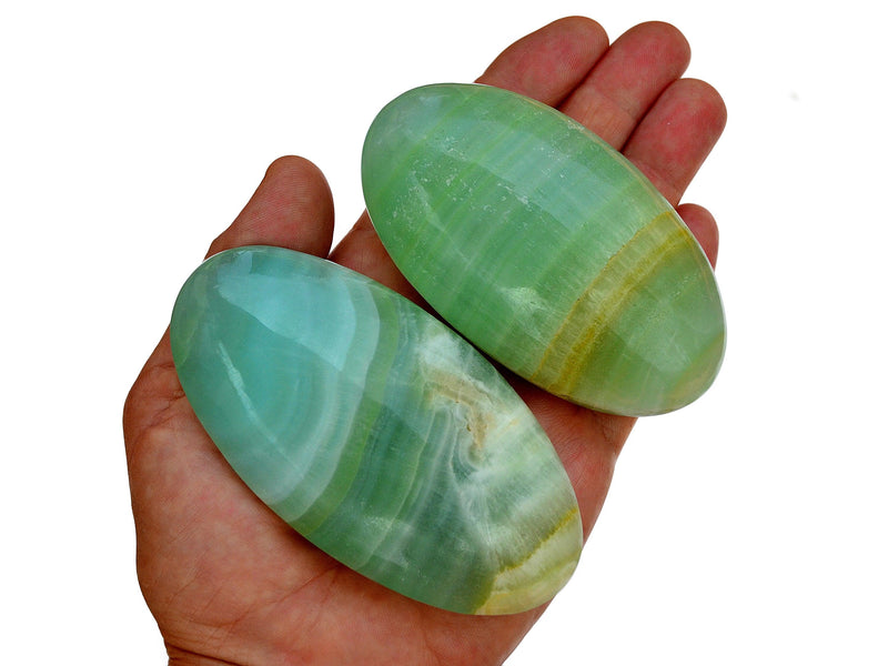 Two pistachio calcite palm stones 85mm-95mm on hand with white background