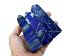 Three blue lapis lazuli tower stones 65mm-100mm on hand with white background