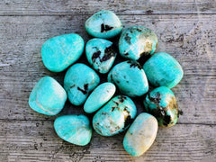 Several large green amazonite tumbled minerals on wood table