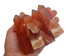 Four honey calcite obelisks crystals 85mm-90mm on hand with white background