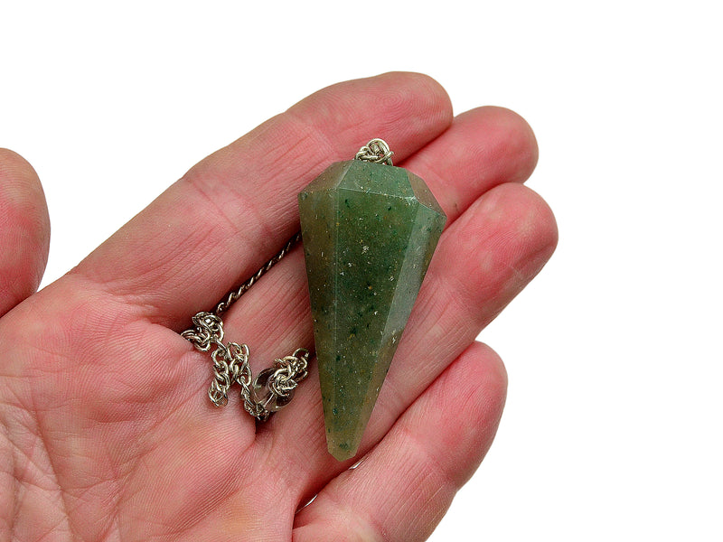Green aventurine pendulum on a silver chain held in a hand on white background