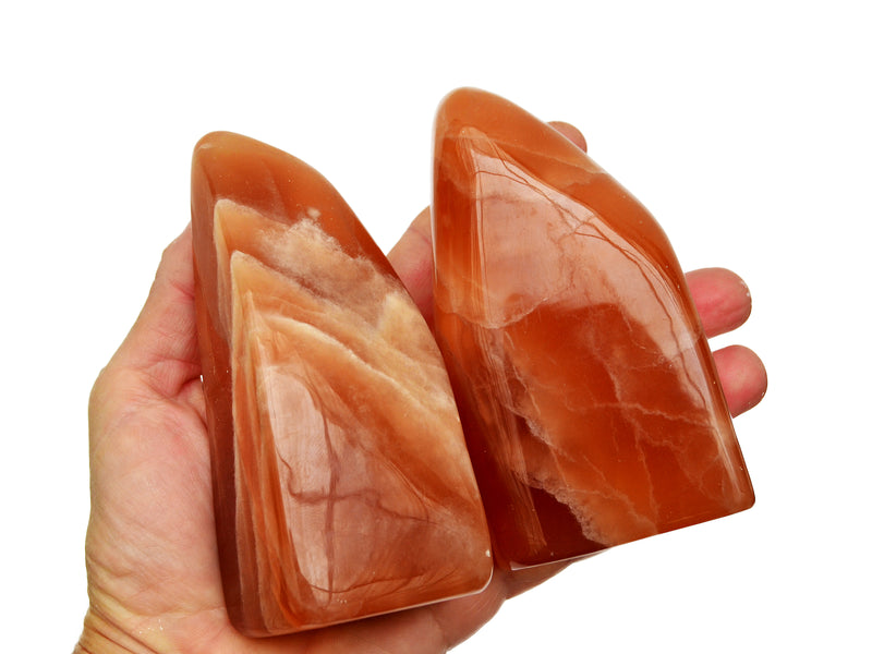 Two large honey calcite free forms on hand with white background