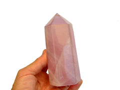 One big pink quartz tower stone on hand with white background