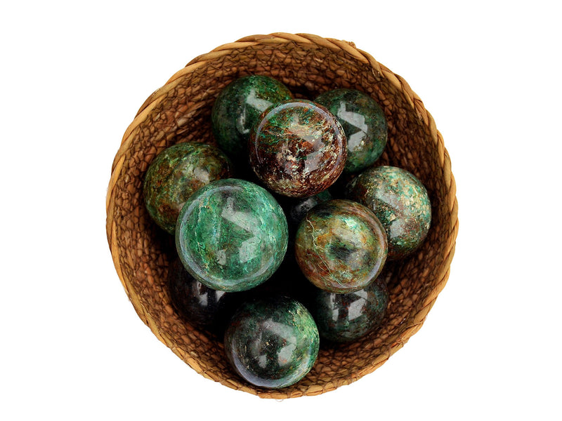 Some green chrysocolla spheres 40mm-65mm inside a straw basket on white background