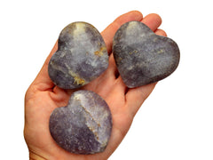 Three purple lepidolite hearts 50mm-60mm on hand with white background