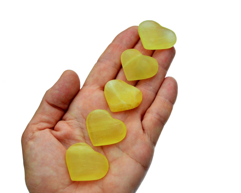 Five small lemon calcite crystal hearts 25mm-30mm on hand with white background