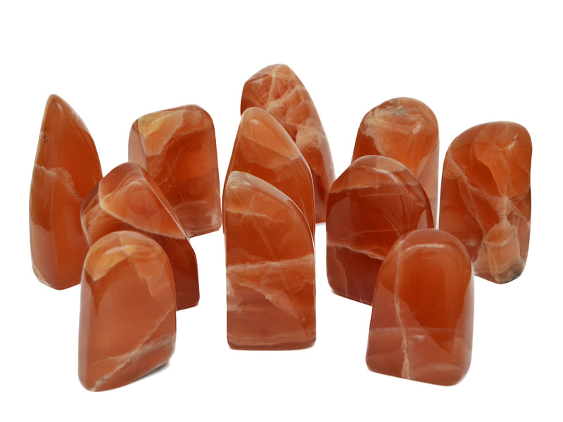 Several honey calcite free form stones 80mm-140mm on white background