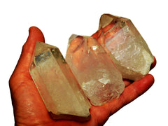 Three large rough clear quartz prisms 140g-180g on hand with white background