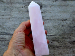 One large and thick pink mangano calcite tower 150mm on hand with wood background