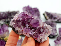 One brazilian druzy amethyst 80mm on hand with background with some stones on white
