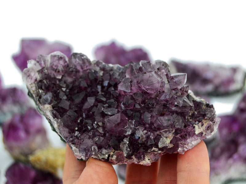 One brazilian druzy amethyst crystal 100mm on hand with background with some stones on white