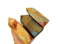 Three chunky polycrome jasper towers on hand with white background