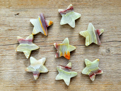 Several pink banded onyx star shapped minerals 55mm-60mm on wood table