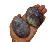 Two purple lepidolite palm stones 65mm-80mm on hand with white background