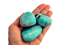 Three big green amazonite tumbled crystals on hand with white hackground