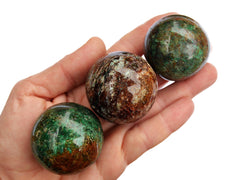 Three chrysocolla crystal spheres 40mm-50mm on hand with white background