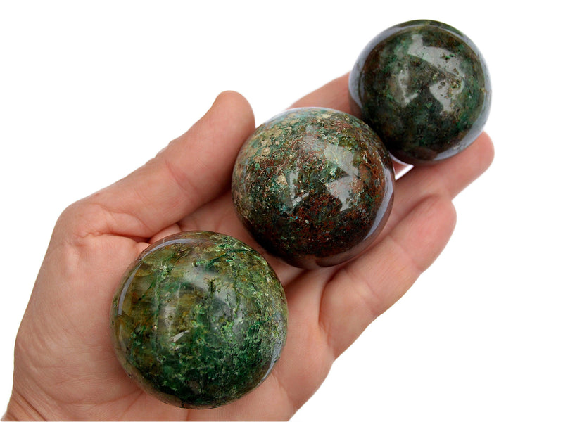 Three chrysocolla crystal balls 40mm-50mm on hand with white background