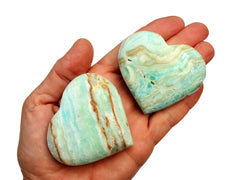 Two large caribbean calcite heart crystals 65mm on hand with white background